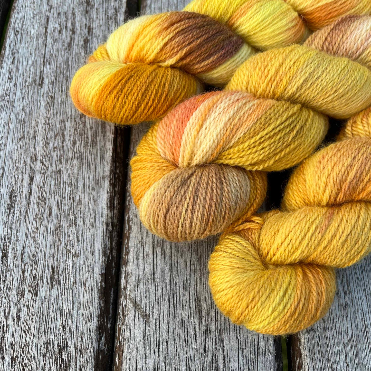 Three skeins of variegated golden yarn peek into the photo, over a wood background.