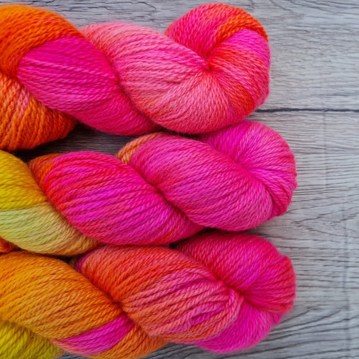 Three skeins of bright pink and yellow yarn.