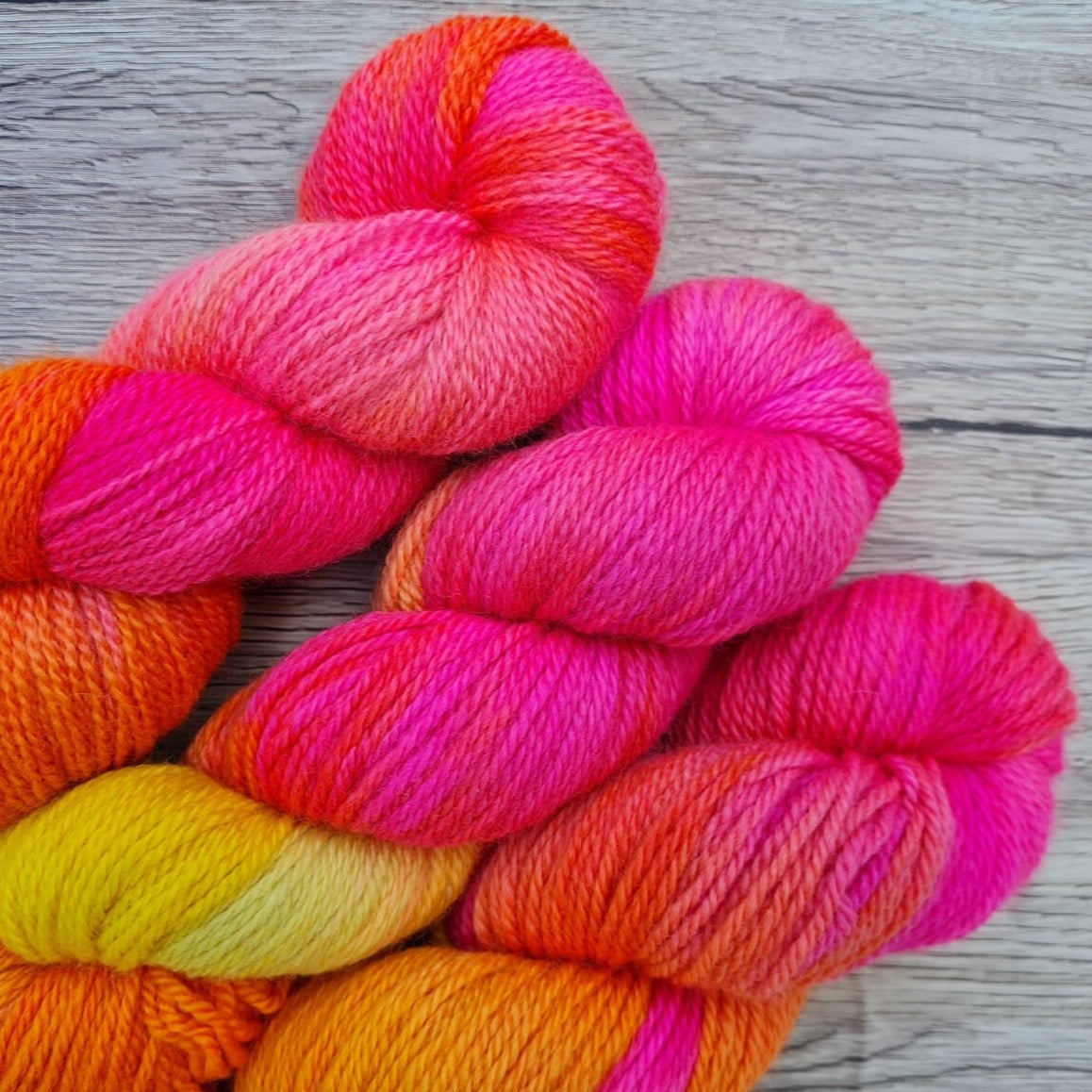 Three skeins of bright pink and yellow yarn.
