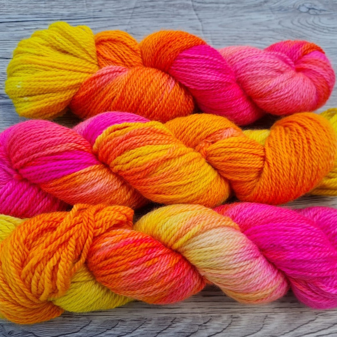 Three skeins of bright pink and yellow yarn.