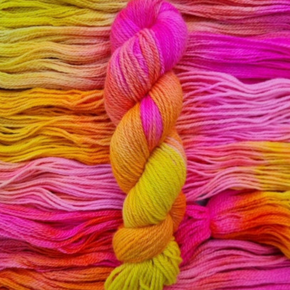 A skein of bright pink and yellow yarn on a background of the same wool.