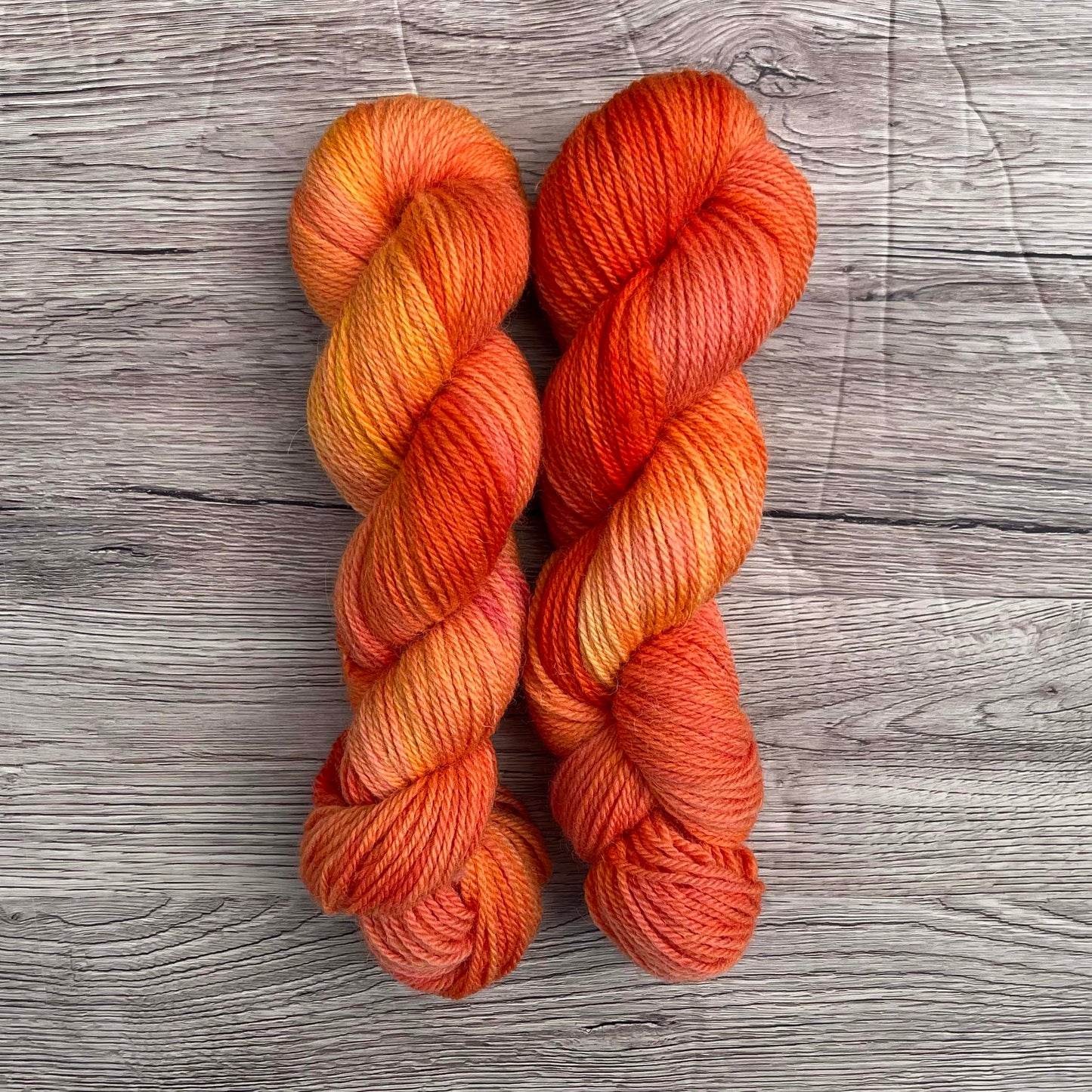 Two skeins of tonal peach yarn on a wood effect background.