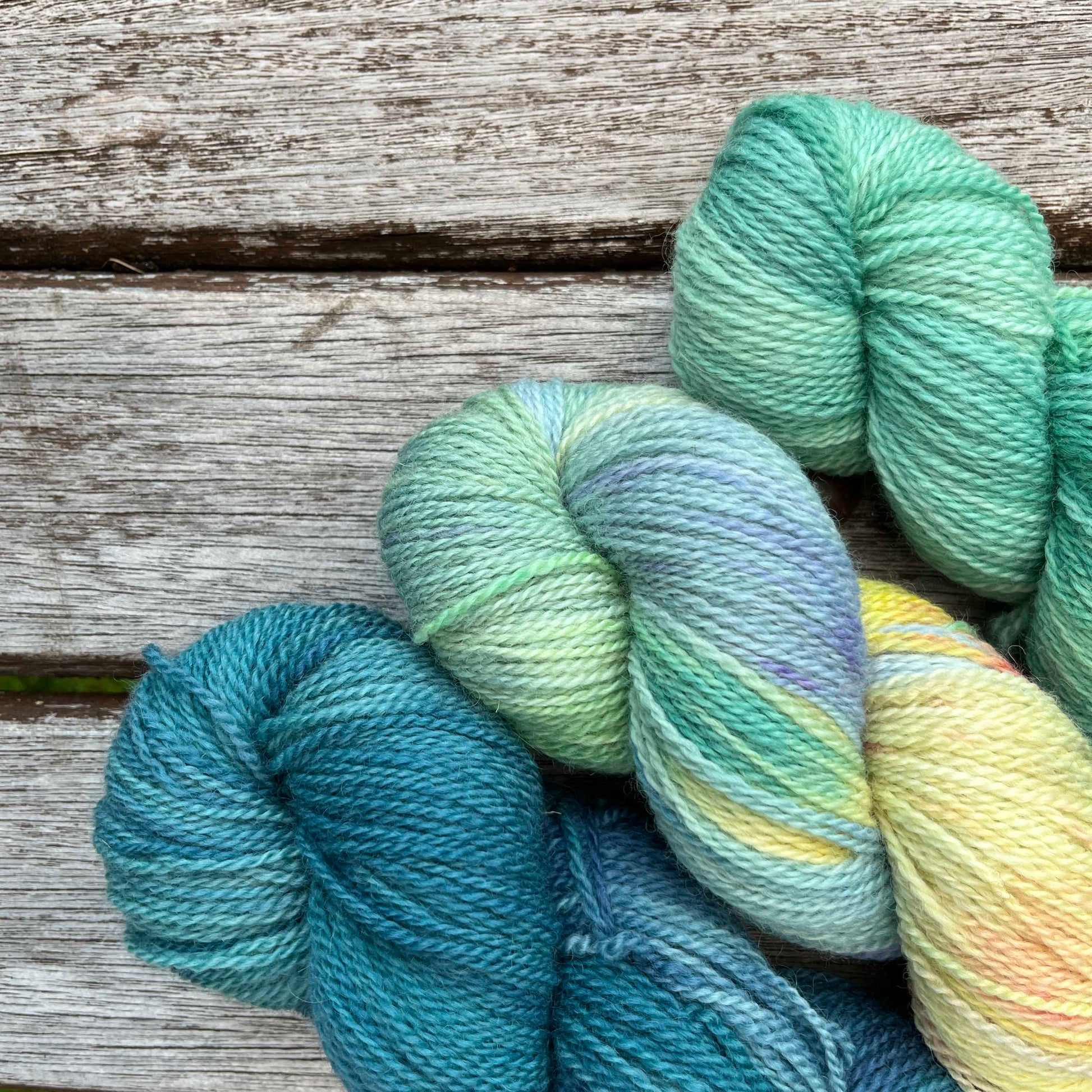 Three skeins of blue and green yarn peek into the corner of the photo.