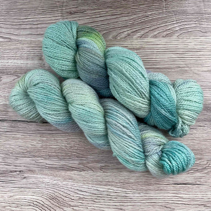 Two skeins of blue yarn on a wood effect background.